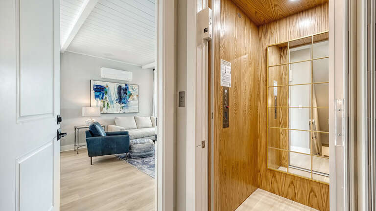 Step through the wood-paneled landing and get your first glimpse of the living room just beyond.