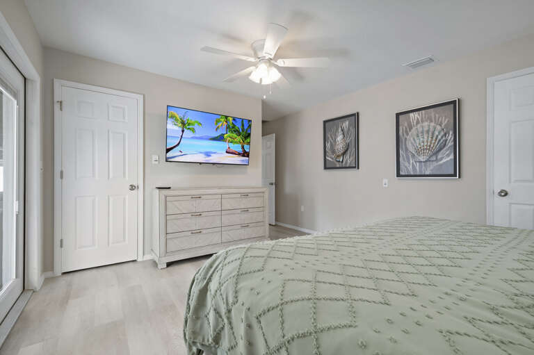 Your own king bed, wall-mounted TV, and framed coastal art — every bedroom in this house was thought through. You will not feel like you drew the short straw.