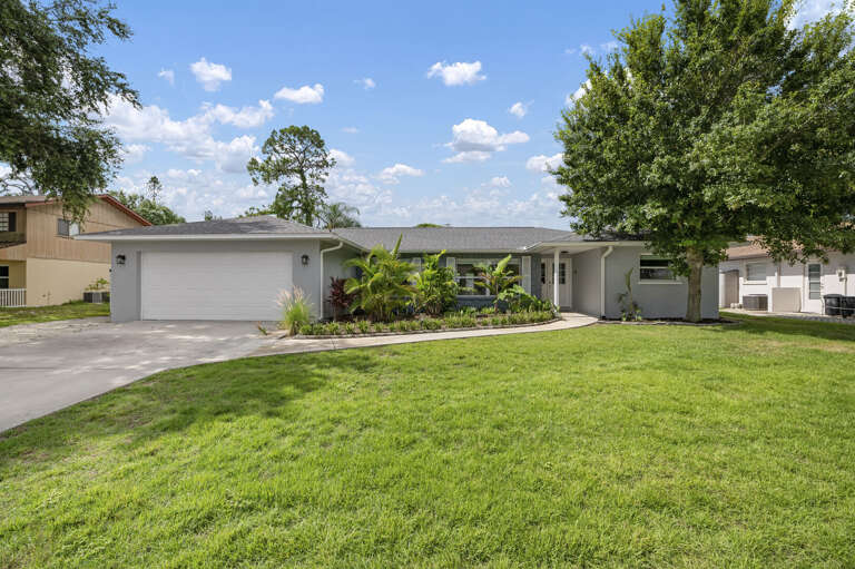 Your rental from the street — gray single-story with a manicured lawn and nothing about it that reads 'vacation rental' to the neighbors.
