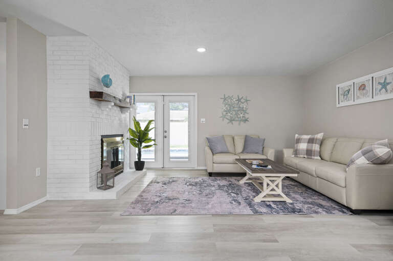 Sink into the cream sectional and the French doors cracked toward the pool — this room works in every season.