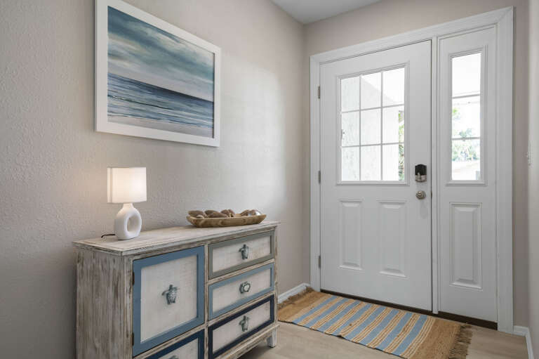 You walk in and the coastal tone is set immediately — ocean art, a thoughtful entryway table, and the sense that someone actually cared how this house welcomes you.