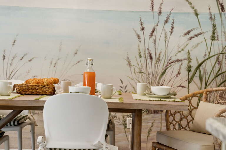 The beach mural wraps behind the dining table and keeps going — it's the kind of thing you notice every morning over breakfast.