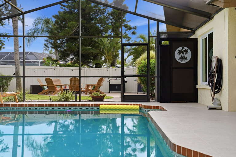 Looking out from the covered lanai, the pool is right there. The screened enclosure keeps everything exactly as it should be — just you and the water.