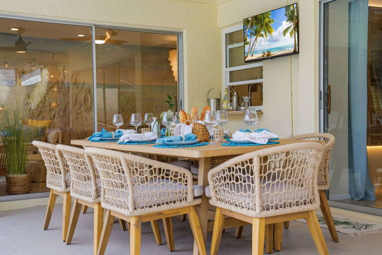 The dining table anchors the covered end; the pool is twenty steps away. Florida living in a single glance.