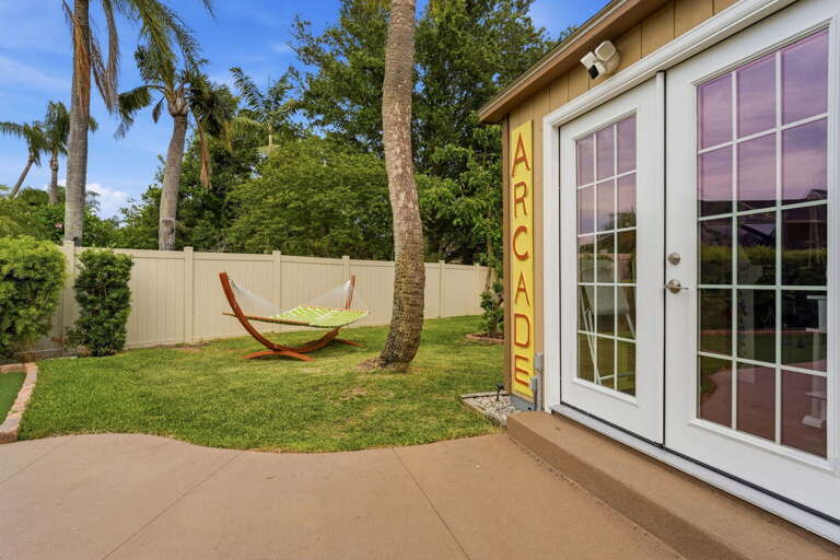 The hammock catches the afternoon breeze between palm trees, five steps from the ARCADE door. Nap or play — it's your call.