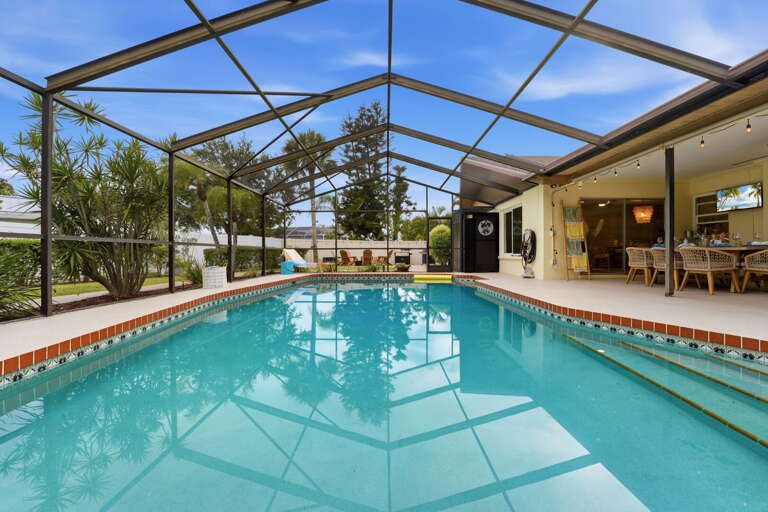 The whole outdoor compound in one shot — pool, covered dining behind, open yard beyond. Plan your afternoon by looking at this picture.