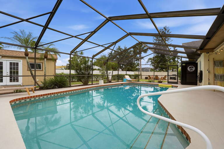 The screened pool compound with the yard and buildings behind it — a reminder this isn't your typical rental backyard.