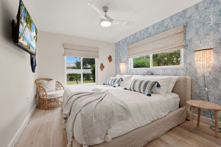 Seashell wallpaper, wood floors, and a king bed — the third bedroom brings the beach theme home in the best way.