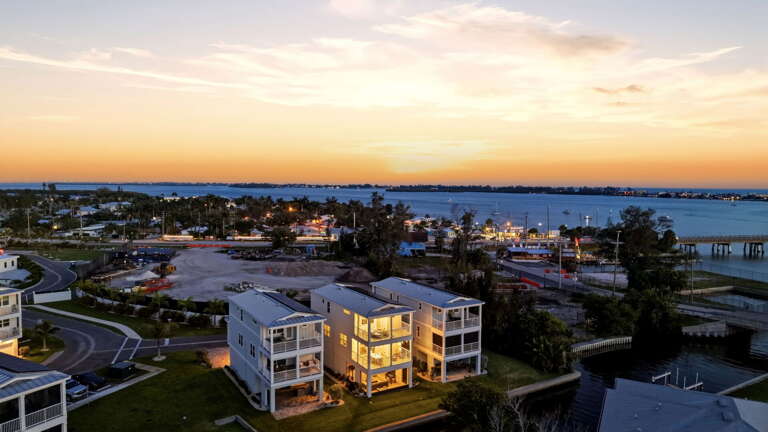 The crown jewel shot - a twilight aerial of the home fully lit and luminous.