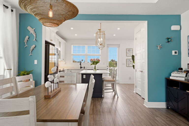 From the dining room, a wide-open view into the kitchen showcases the navy island, gold lantern pendants, white cabinetry