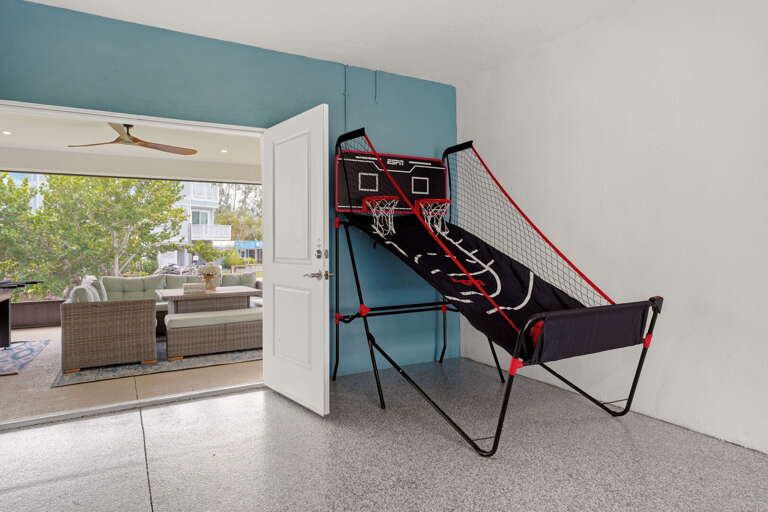 The ESPN dual-hoop basketball arcade game anchors the fun zone, with a direct view through to the breezy enclosed lounge beyond.