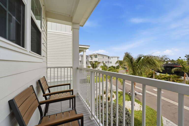 A front-facing second-floor balcony with two slatted chairs is the perfect spot to enjoy the tropical breeze and take in the palm-lined street views.