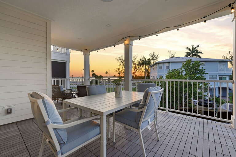 Golden hour dining al fresco - the covered rear deck shines at sunset with a six-seat white outdoor dining table