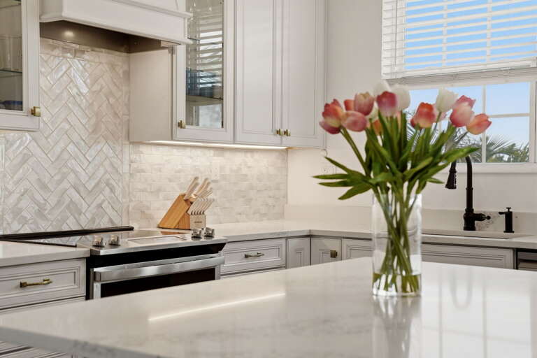Kitchen detail showcasing the herringbone marble-look backsplash, under-cabinet lighting, quartz counters, slide-in gas range