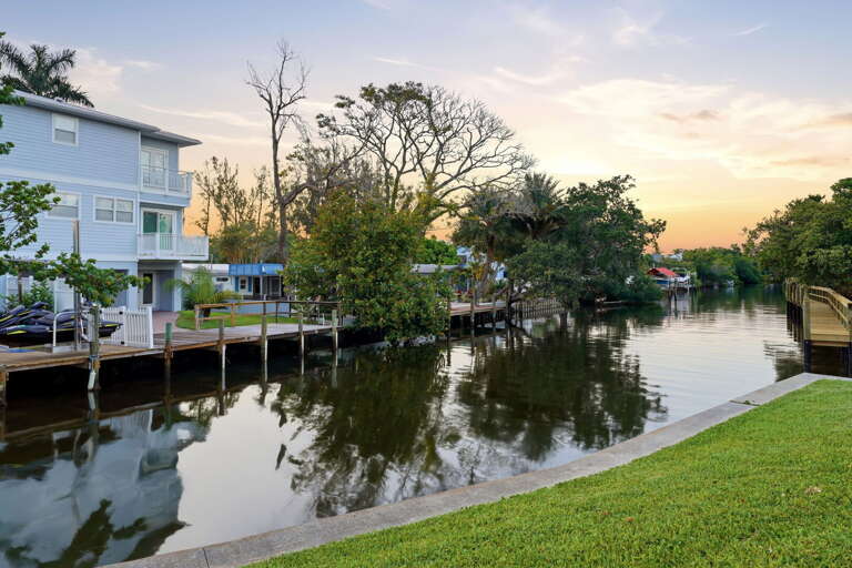 A peaceful canal-side evening view from ground level - the tree-lined waterway stretches quietly into the distance