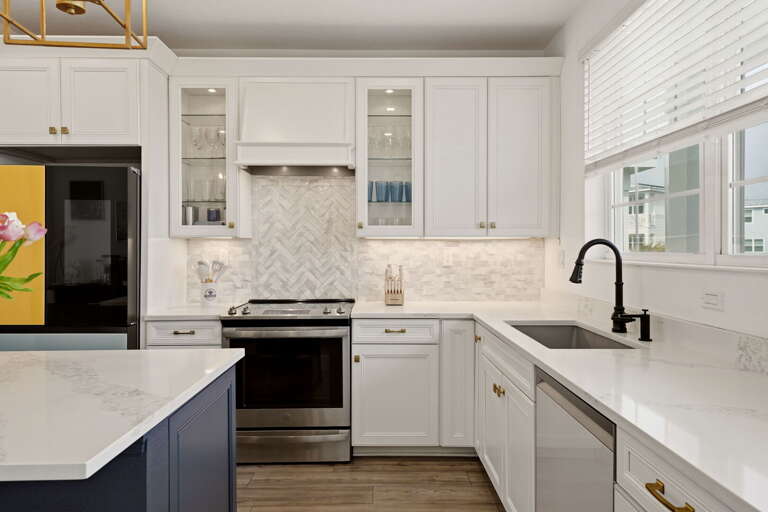 Upper kitchen cabinetry detail features glass-front display cabinets, custom hood, Samsung Bespoke refrigerator