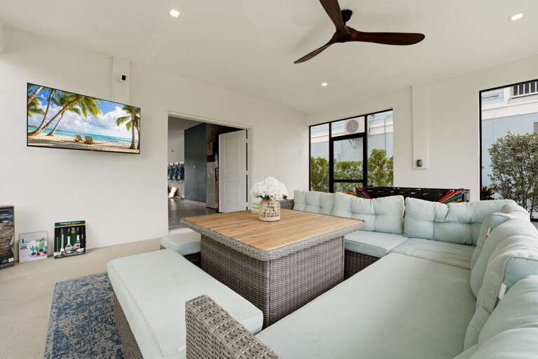 A wall-mounted flat-screen TV and ceiling fan make this enclosed porch is a true all-season living space,