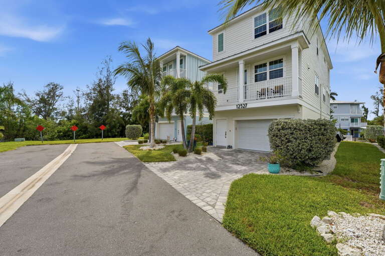 Welcoming curb appeal with manicured tropical landscaping, a paver driveway, and an oversized two-car garage