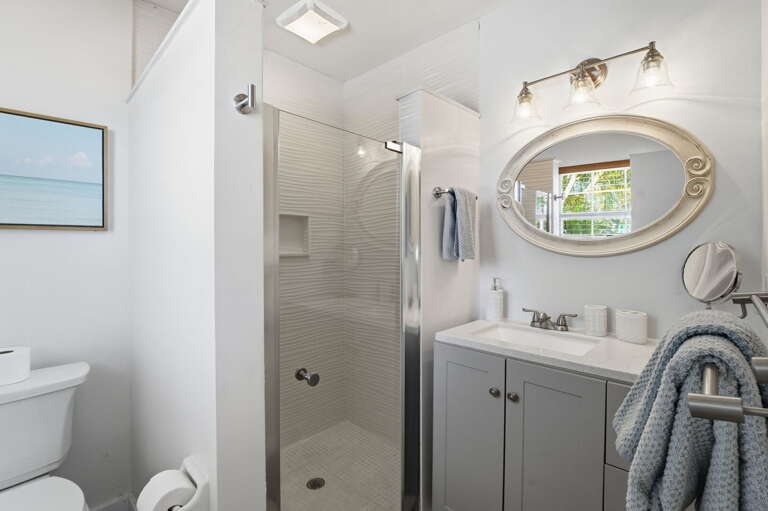 Step in and rinse off after the pool -- full shower enclosure, bright light, oval mirror, and everything in good shape.