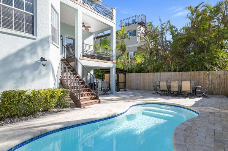 Your chair is waiting by the heated pool — three levels of balconies rise behind it, a wall of palms on all sides, and someone always watching from up top.