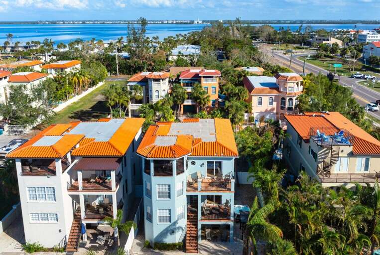 Close aerial of the terracotta-roofed buildings surrounded by palms — this is the Anna Maria Island character that makes it feel like nowhere else on the Gulf Coast.