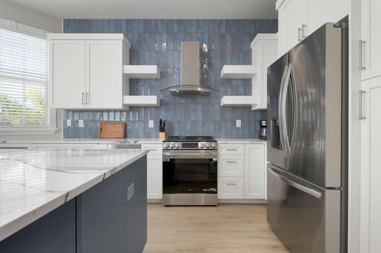 Your full-width kitchen has blue-grey lowers, white uppers, a stainless range with hood, and enough counter space to actually cook for eight people without a problem.