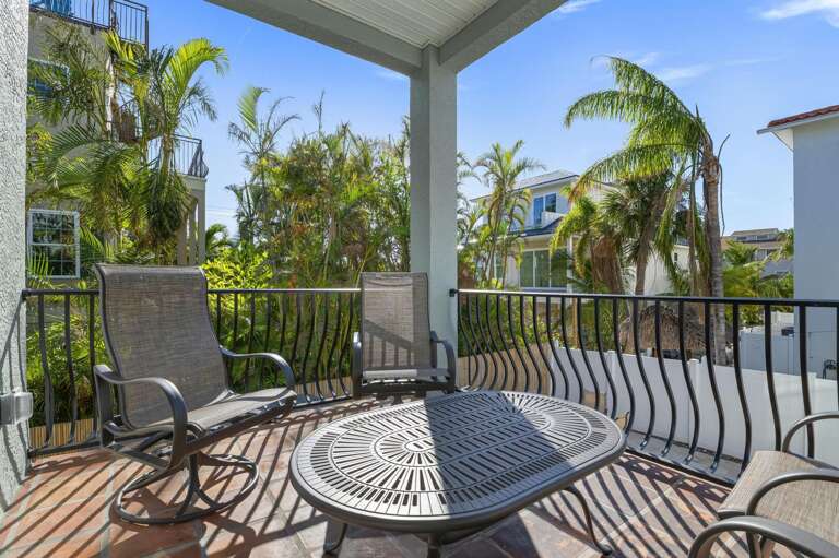 Step out here and you're completely wrapped in dense palms — the covered balcony is more private than you'd expect for a property two blocks from the beach.