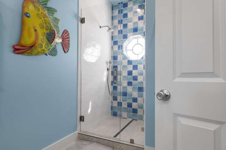 Stop in front of the blue tile walk-in shower and look at the fish wall sculpture — it's the kind of detail that makes guests take a photo before they even unpack.