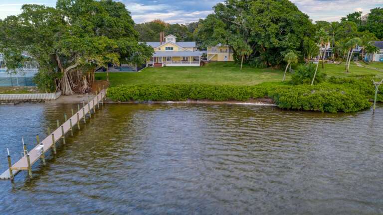 Watch the path run from the back porch straight down to the dock — that's the walk you'll be making every single morning for coffee by the water.