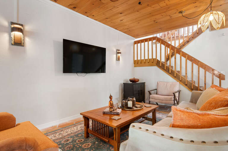 Claim the sofa, flip on the wall-mounted TV, and let the staircase remind you there are two full floors of space to explore whenever you feel like it.