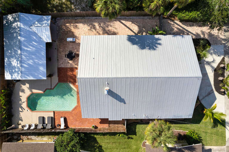 Find your shade under the tree canopy that wraps the whole yard. From above, the pool is the clear center of gravity for everything happening here.