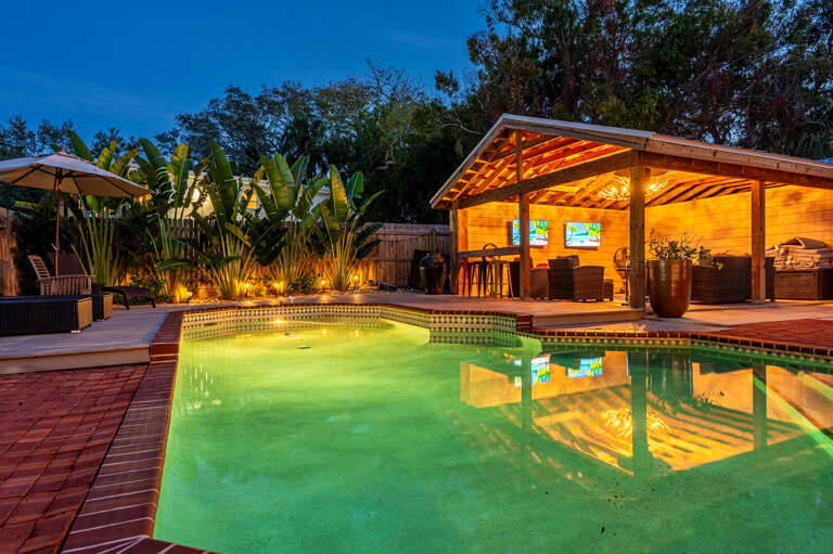 Float in warm water while the cabana TVs run and the tropical plantings close in around you. The pool deck at night is where this house becomes unforgettable.