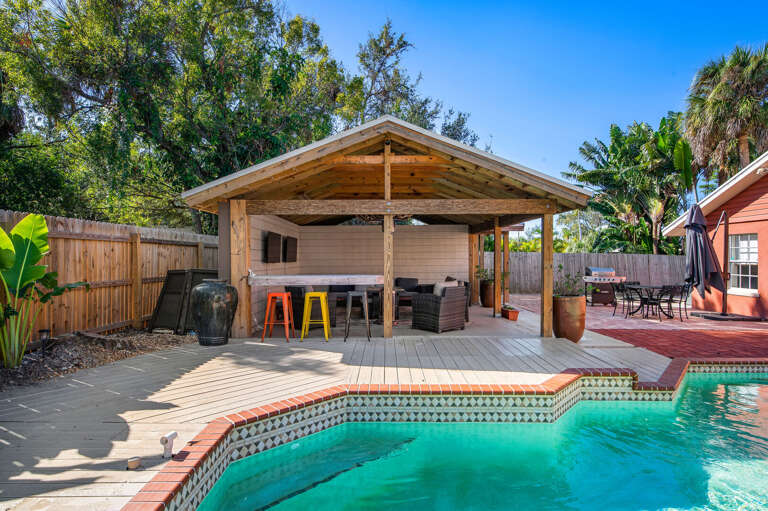 Pull up a stool at the tiki bar, pour your own round, and settle in. Yellow bar stools, poolside shade, and the whole afternoon to burn through it.