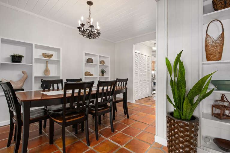 Sit down for dinner under a real chandelier at a dark wood table for six. The built-in sideboard holds the rest — breakfast through late dinners, this room earns it.