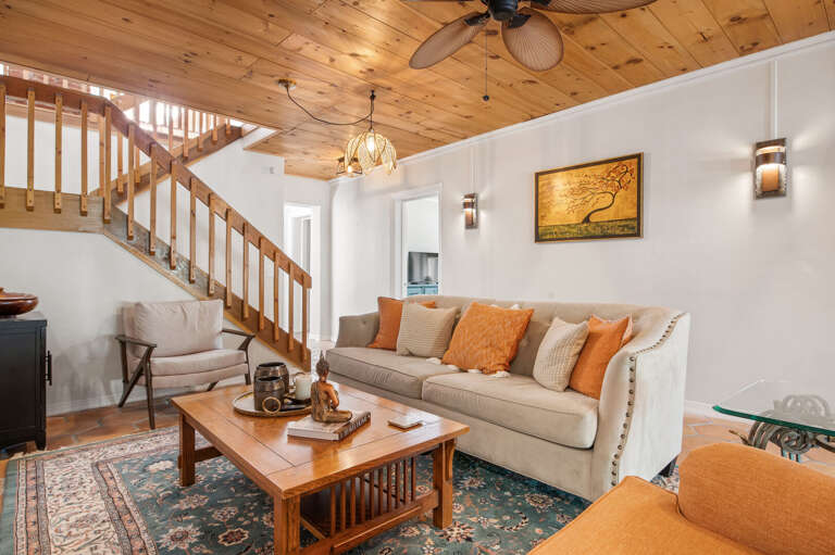 Sit anywhere in the living room and still be part of the conversation. The original wood staircase anchors the room, and the space is bigger than it photographs.