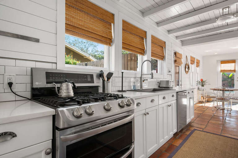 Start a real meal on a proper gas range with a kettle already on the burner and subway tile behind everything. This kitchen was set up for someone who actually cooks.