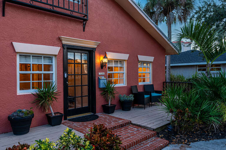 Step up to the front door at twilight: black French door, warm sconce light, and the kind of entrance that makes arriving feel like the beginning of something good.