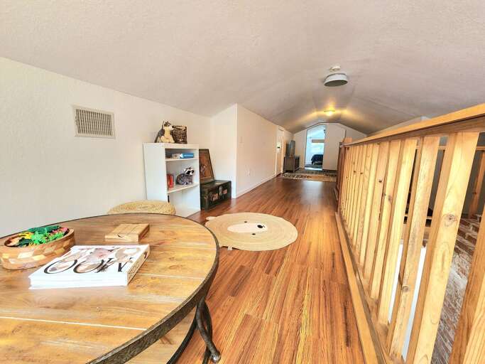 Walk the loft hallway and the wood railing runs all the way to the end. The upstairs has a layout that makes the whole house feel twice as spacious.