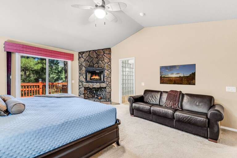 Primary Suite 1- Main Level: King-size bed, pull-out couch, decorative stone fireplace, flat-screen TV, private access to the upper deck, and en suite bathroom Primary Suite 1- Main Level: King-size bed, pull-out couch, decorative stone fireplace, flat-screen TV, private access to the upper deck, and en suite bathroom