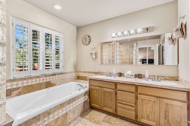 Primary suite bathroom with a double vanity, walk-in tiled shower, and jetted tub. Primary suite bathroom with a double vanity, walk-in tiled shower, and jetted tub.