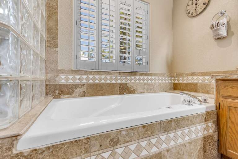 Primary suite bathroom with a double vanity, walk-in tiled shower, and jetted tub. Primary suite bathroom with a double vanity, walk-in tiled shower, and jetted tub.