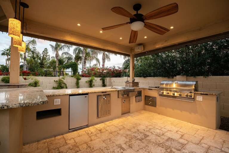 Outdoor kitchen and bar with BBQ Grill, sink and fridge.