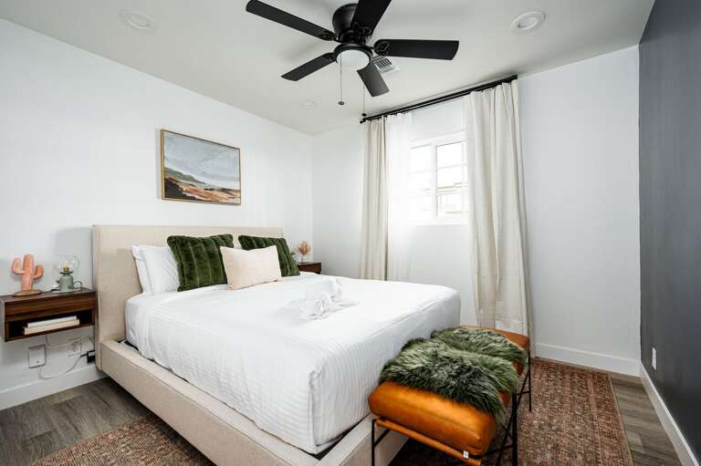 Third bedroom with floating nightstands and a bench at the end of the bed.