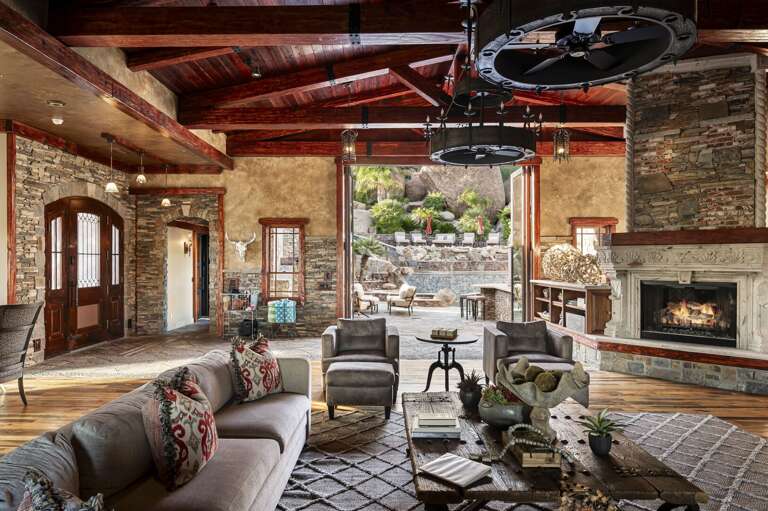 Gather in the spacious living room featuring soaring wood-beamed ceilings, elegant furnishings, and rustic luxury throughout.