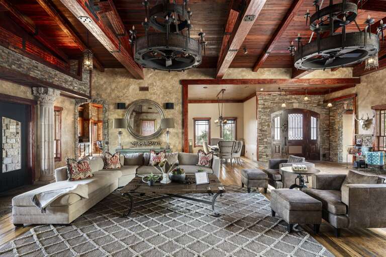 Relax in the grand living room featuring soaring wood-beamed ceilings, elegant furnishings, and spacious seating perfect for gathering.