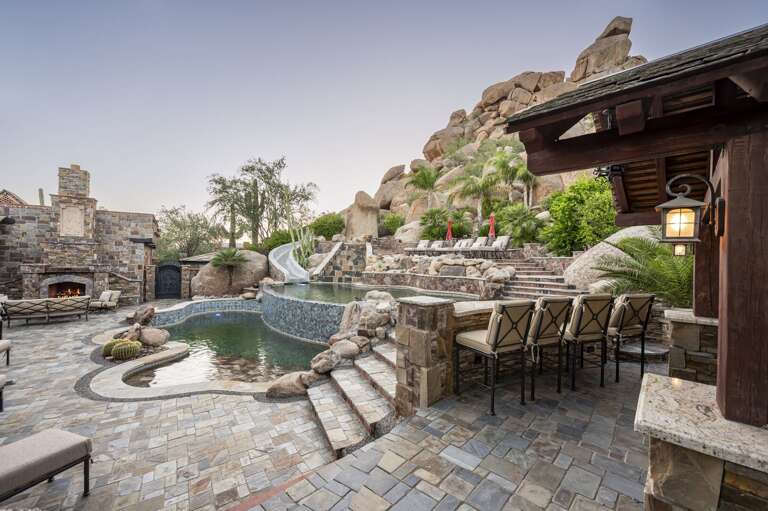 Enjoy a luxurious outdoor retreat featuring a stunning pool, waterslide, and inviting poolside seating.