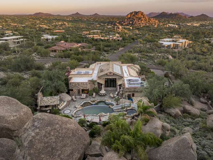 Discover a secluded desert oasis surrounded by breathtaking mountain views, natural boulders, and stunning Sonoran Desert scenery.