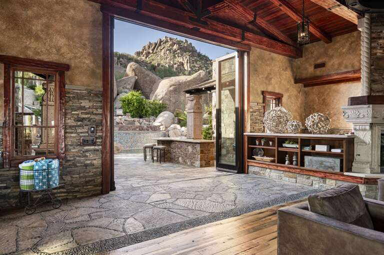 Enjoy seamless indoor-outdoor living with expansive doors opening to a stunning poolside retreat and dramatic desert boulder views.