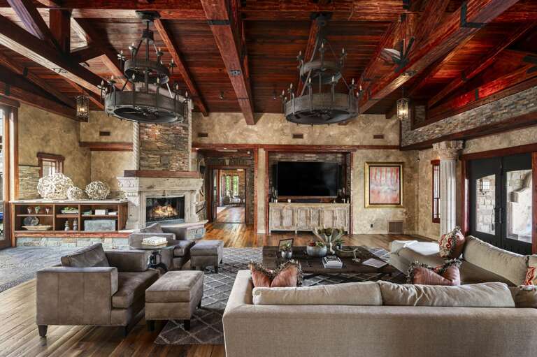 Gather in the spacious living room featuring soaring wood-beamed ceilings, elegant furnishings, and rustic luxury throughout.