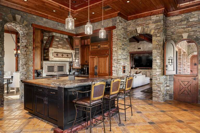 Gather in the beautifully designed gourmet kitchen, featuring rich wood cabinetry, expansive islands, elegant stone finishes, and a charming breakfast nook with stunning desert views.